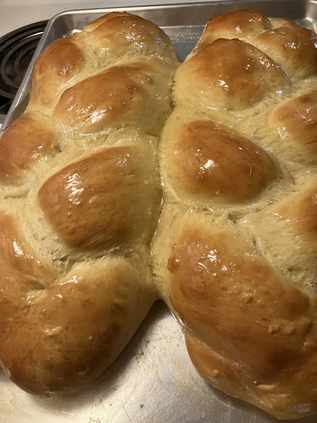 Golden homemade bread rolls cooling on a tray.