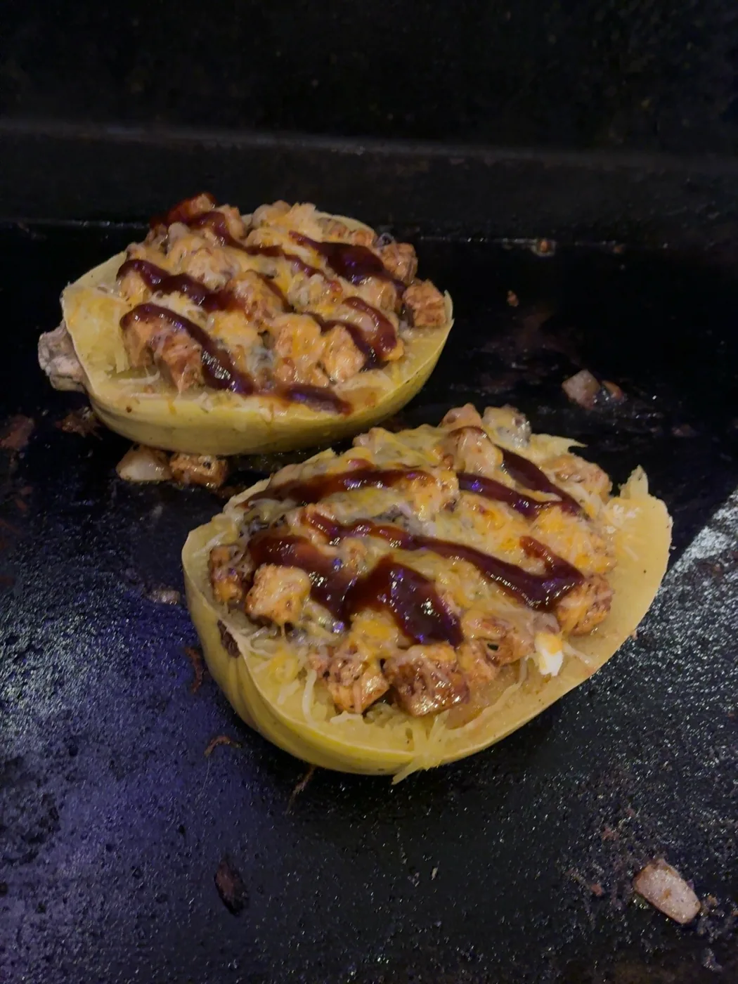 Two squash halves piled with colorful toppings on a baking tray.